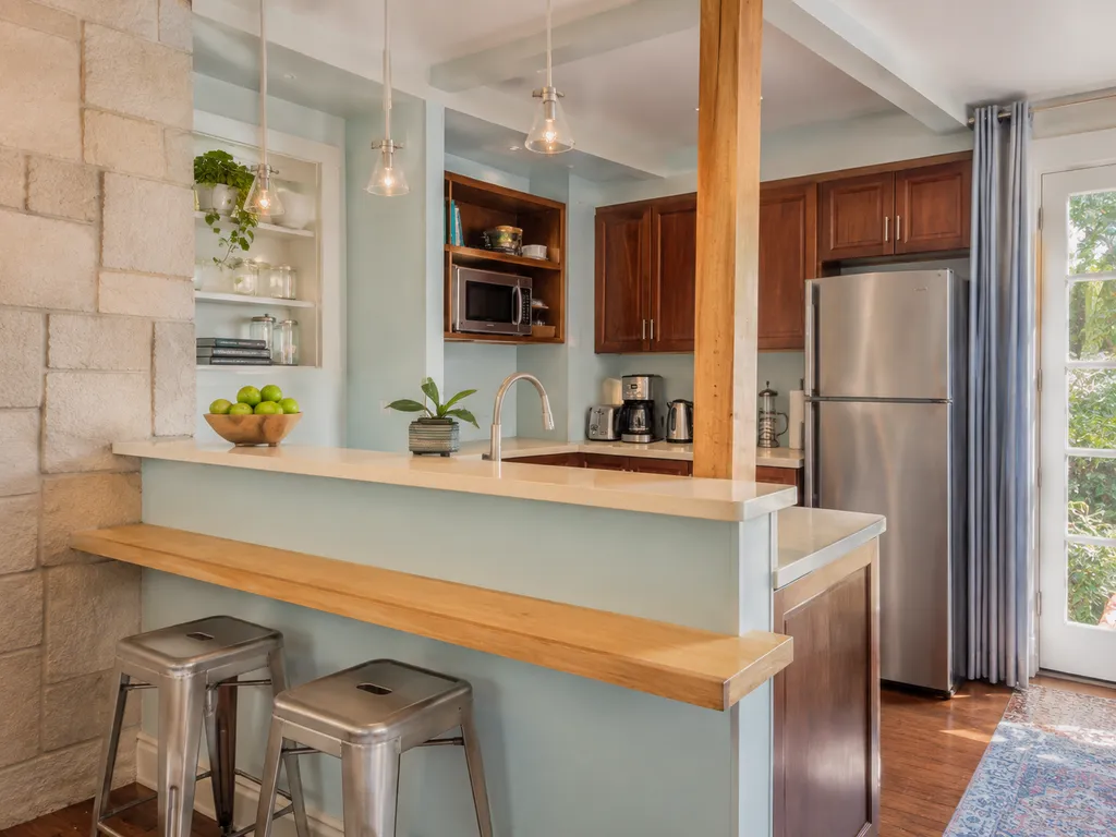 A kitchen with a breakfast bar, stools, and a refrigerator.